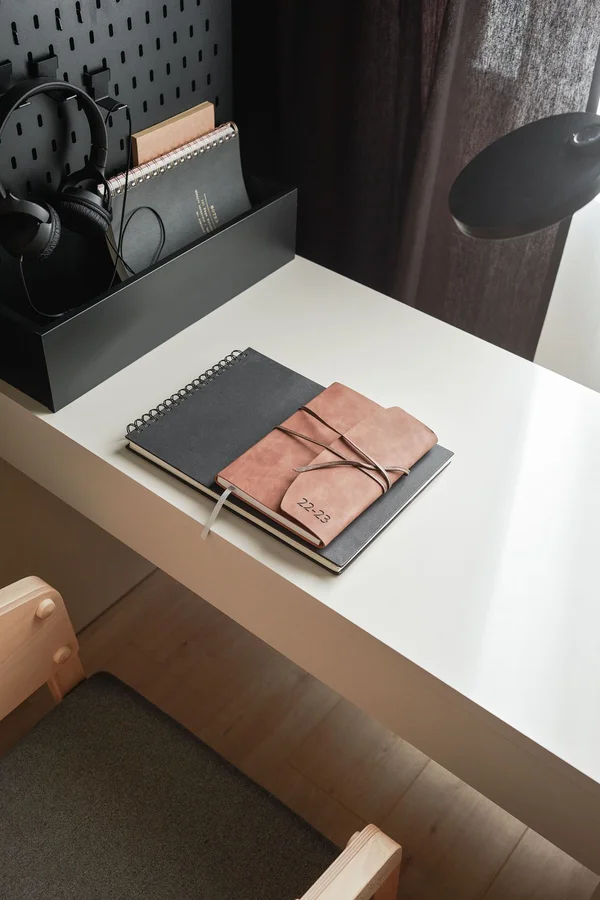Minimalistyczne biurko z organizerem na akcesoria, notatnikiem i eleganckim kalendarzem, idealne do zarządzania dokumentami i codziennymi notatkami.